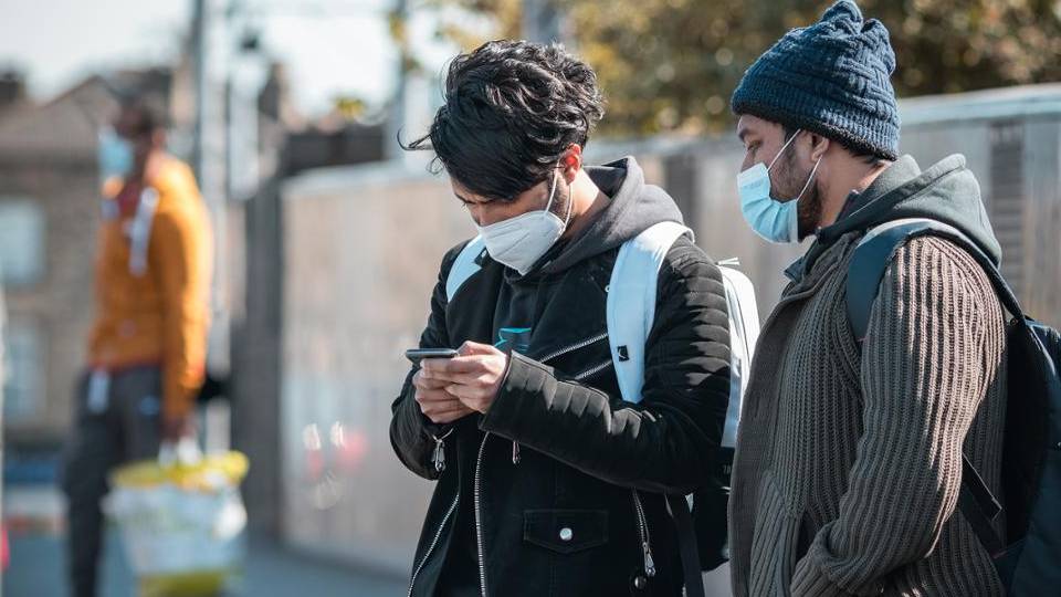 Two guys wearing face masks while checking on the phone