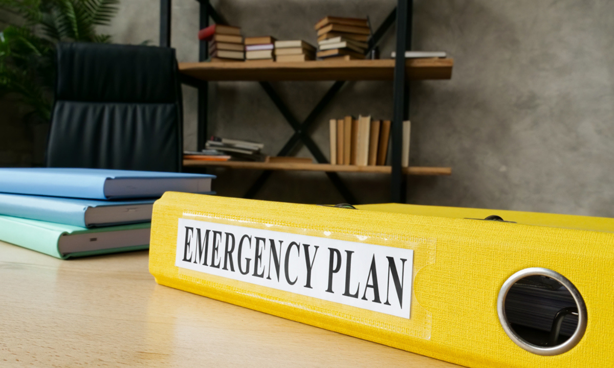 Yellow folder with emergency plan written on it. On a desk