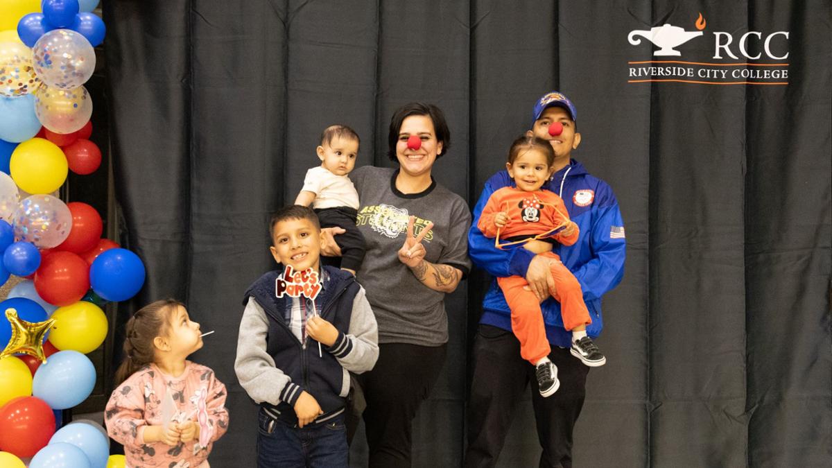 EOPS student and their families in front of a banner with clown noses on their faces