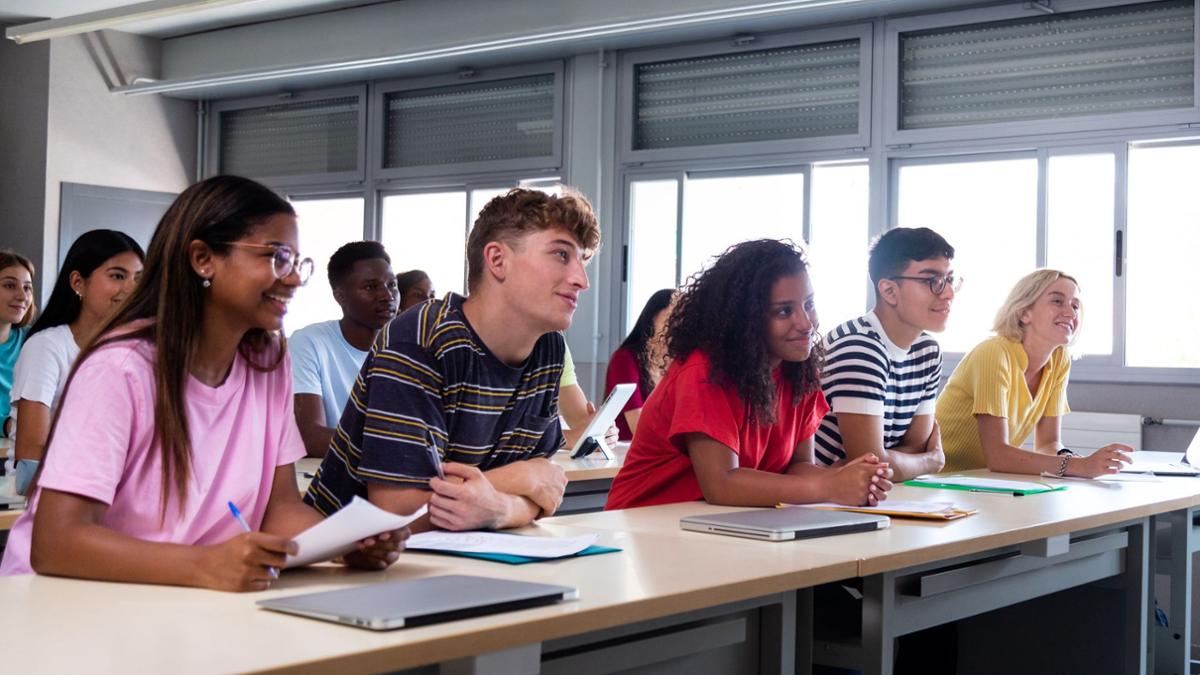 Students sitting at a table looking towards a guest speaker who is off camera