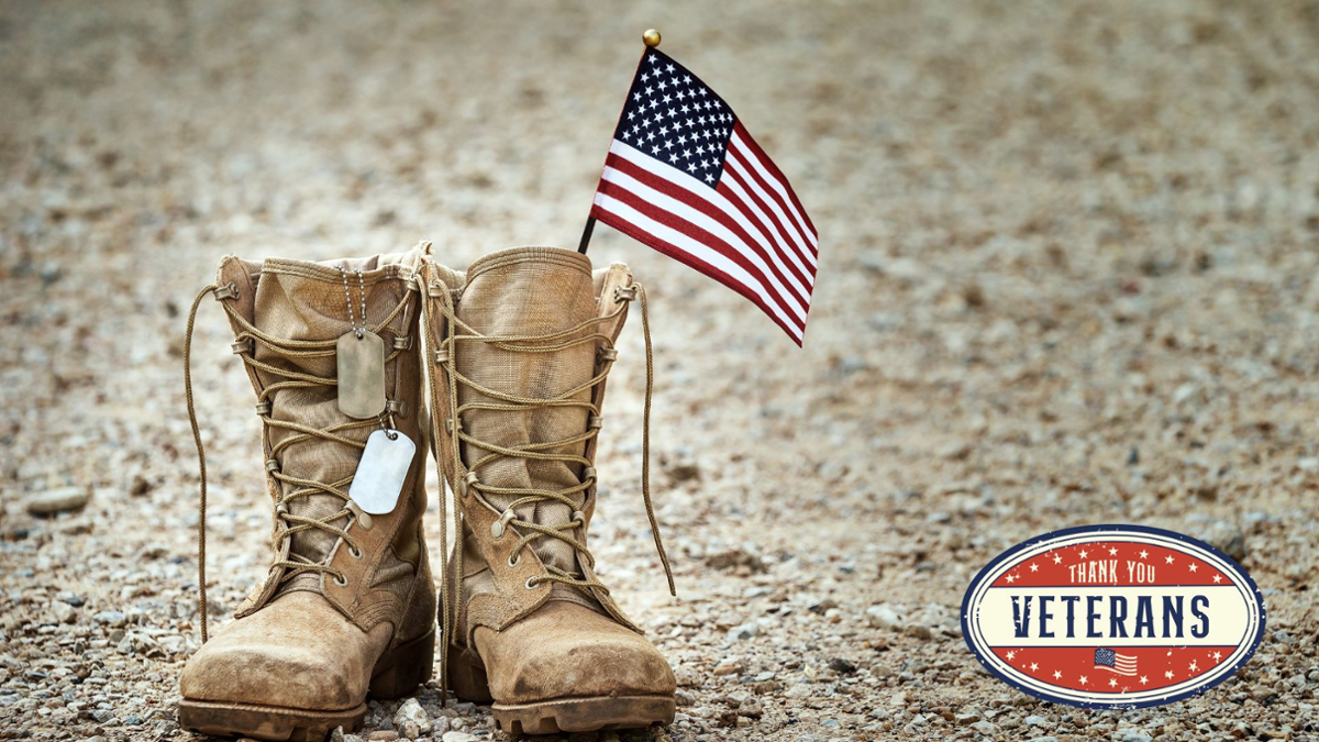 Army boots-beige with an American Flag and dog tags on the boots. Gravel Background. Bottom right corner, Thank you Veterans