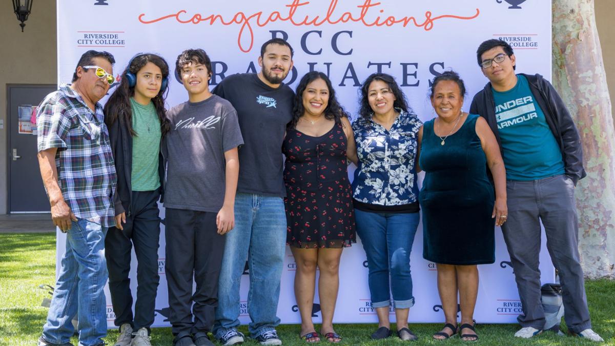 RCC graduate poses with family members in front of a “Congratulations RCC Graduates” backdrop during Grad Fest 2026, celebrating academic achievement and the upcoming commencement ceremony.