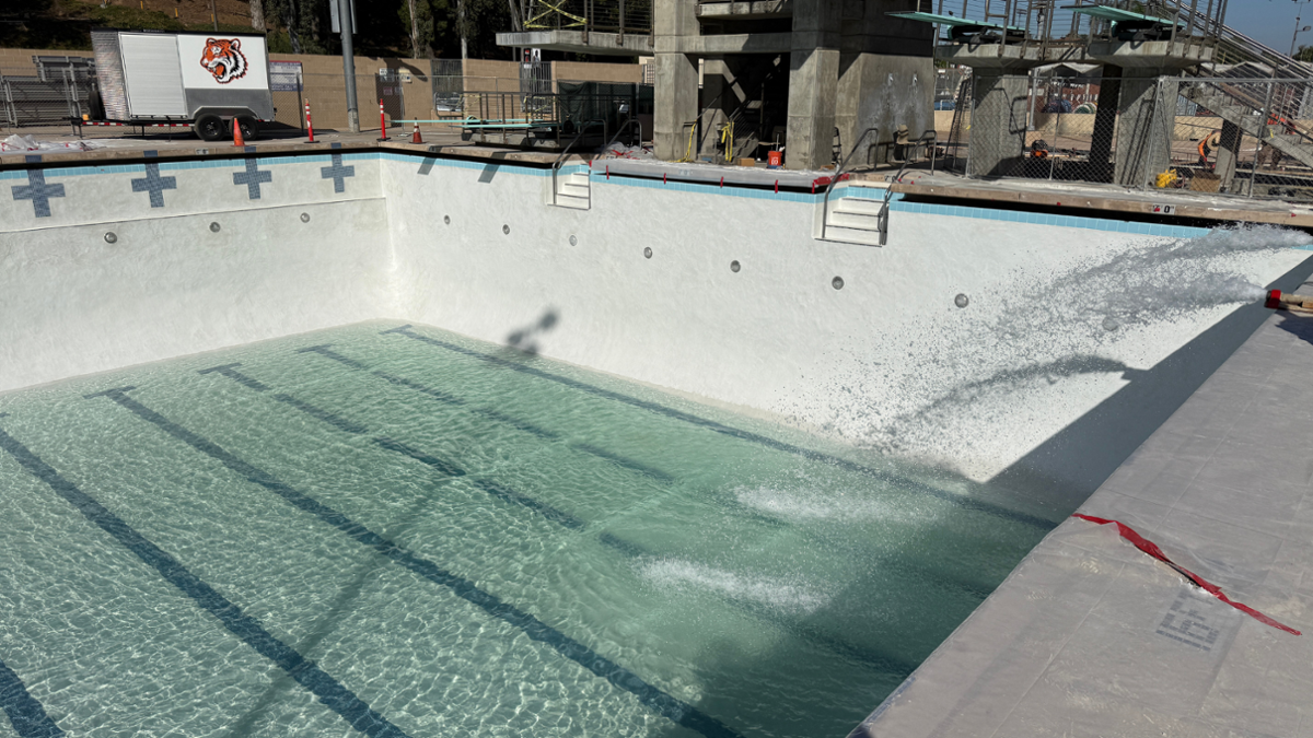 Refurbished Riverside City College swimming pool during renovations, showing the newly resurfaced pool basin filled with water and surrounding deck improvements.