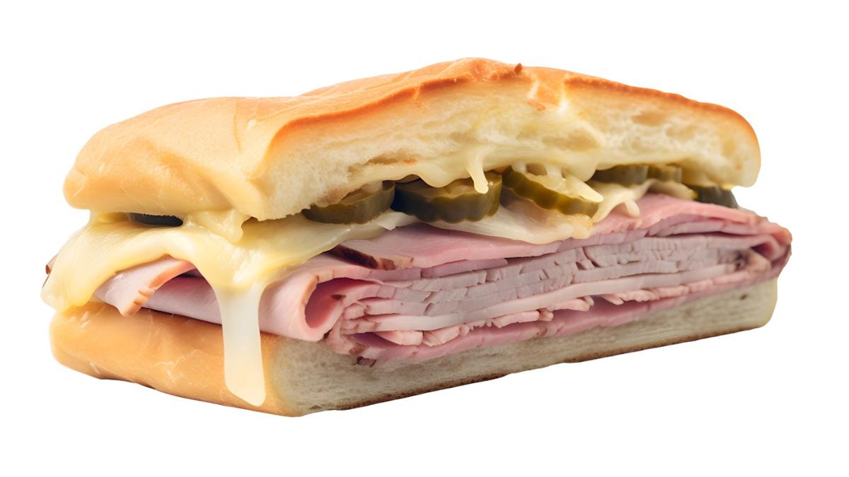 A close-up of a Cuban-style sandwich on white background, filled with sliced ham, roasted pork, melted cheese, and pickles inside a toasted soft roll.