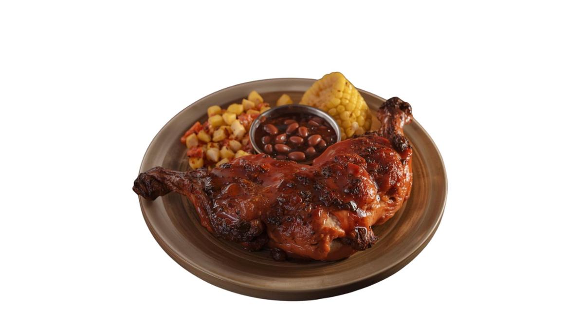 Plated BBQ chicken quarter glazed in sauce served with baked beans, seasoned diced potatoes, and a corn on the cob, arranged on a brown dish against a white background.