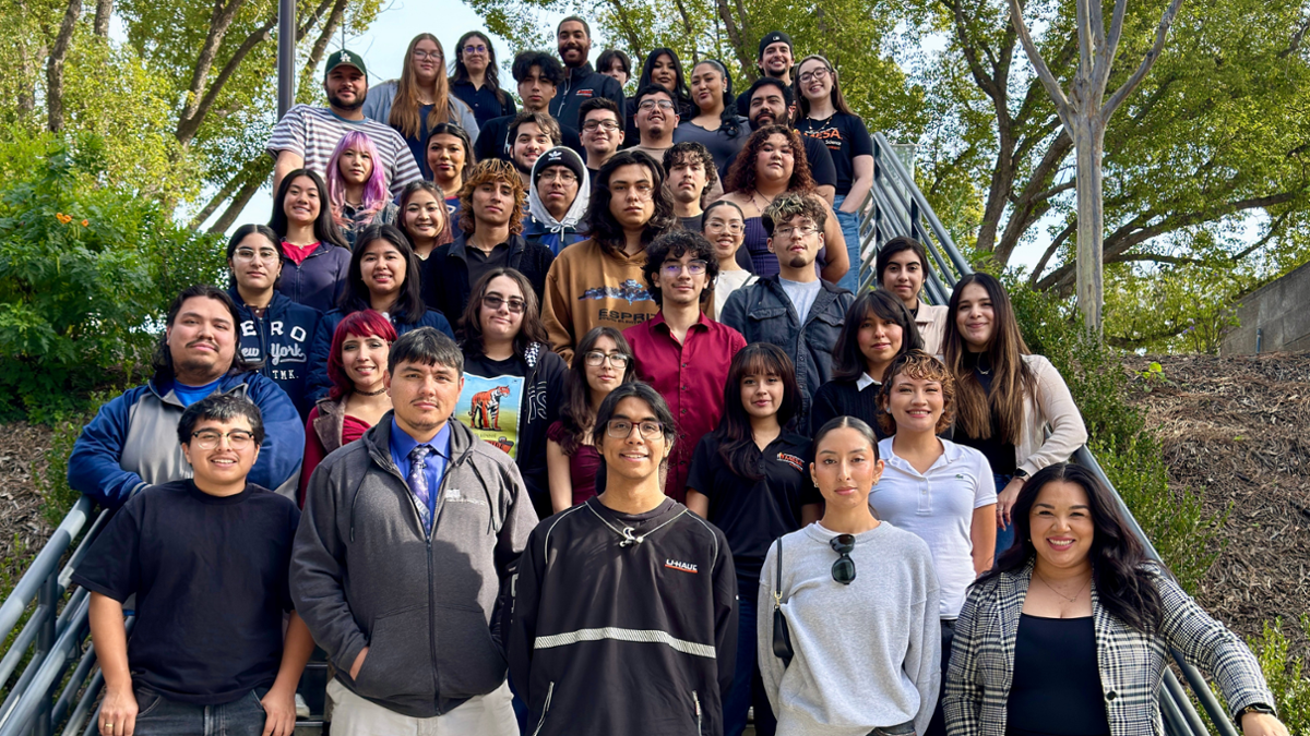 Group photo of RCC MESA students and staff standing together on outdoor campus stairs surrounded by trees, smiling toward the camera.