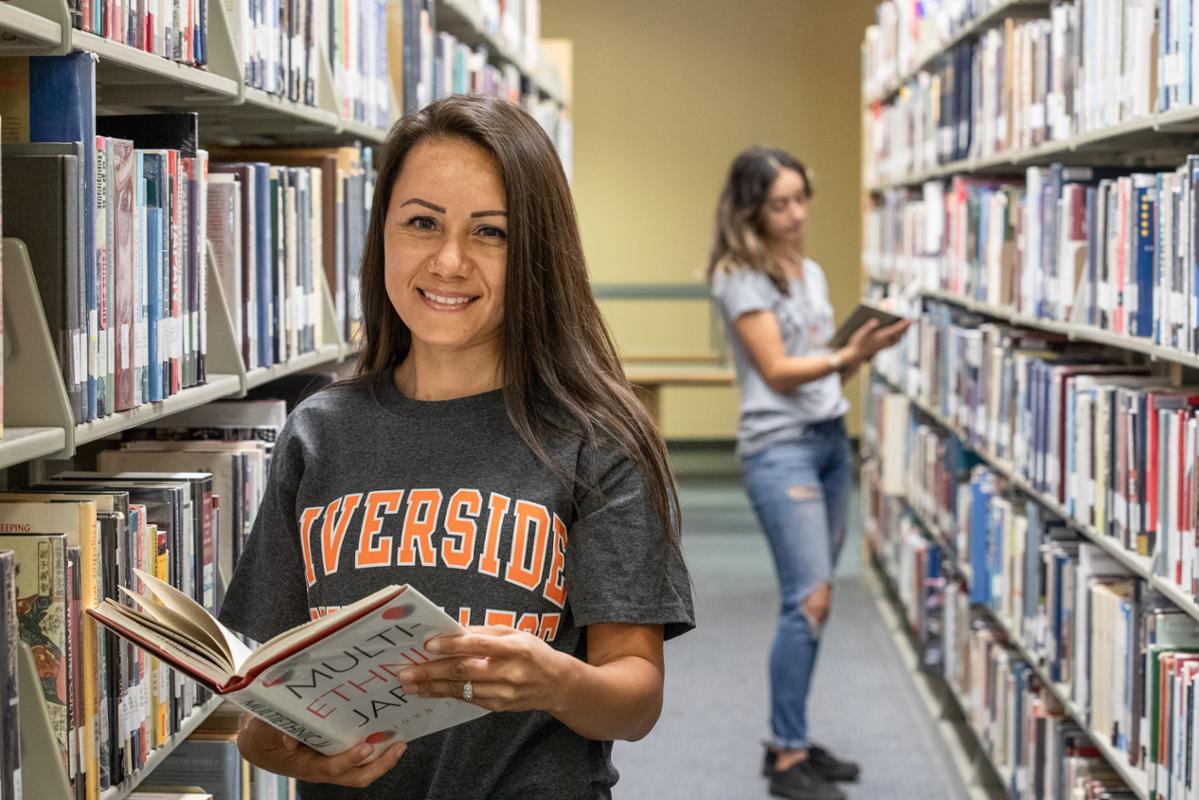 Student in library - stacks of books behind them